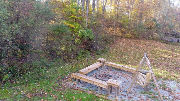 A campsite with a fire pit and picnic tables surrounded by trees and foliage. - Spacious Bobcat Cabin, 30 mins from Hocking Hills (Nelsonville)