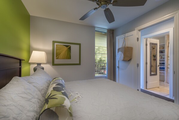 A bedroom with a bed, a ceiling fan, a window with curtains, and a door leading to a closet.