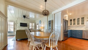 A dining area with a round wooden table, white chairs, and a ceiling fan.