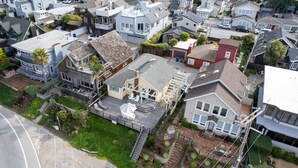 An aerial view of a residential area with various houses, including a house with a visible deck and a garage.