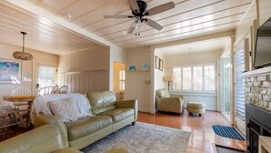 A spacious living room with a ceiling fan, a fireplace, and a large window.