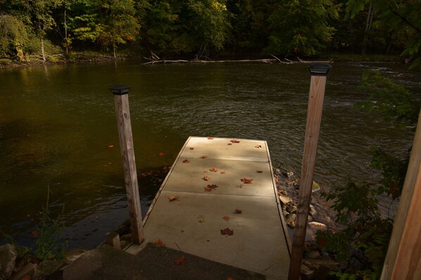 A concrete dock extending into a river surrounded by trees.
