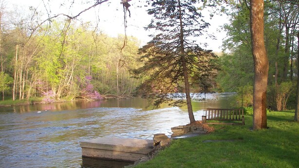 A riverside park with a concrete dock, a wooden bench, and a stone wall. - The River House of Alaska, Michigan located Southeast Grand Rapids, pet friendly (Alto)