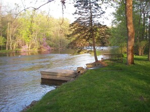A riverside park with a concrete dock, a wooden bench, and a stone wall.