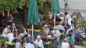 An outdoor café with wooden tables and chairs, surrounded by potted plants and umbrellas. - Hotel Restaurant Zum Engel (Roemerberg)