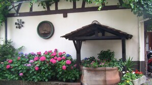 A building with a white exterior, a wooden pergola, and a large flower bed with pink and purple flowers. - Hotel Restaurant Zum Engel (Roemerberg)