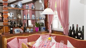 A restaurant with a checkered tablecloth, wooden furniture, and a variety of bottles and pottery on shelves. - Hotel Restaurant Zum Engel (Roemerberg)