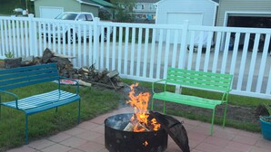 A patio area with a fire pit, benches, and potted plants.