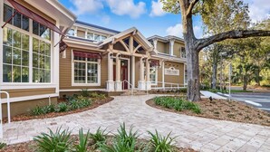 A two-story building with a covered entrance, a sign reading "The Oaks", and a paved walkway with landscaping.