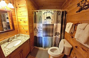 A wooden cabin bathroom with a sink, toilet, and shower curtain featuring a patchwork design. - WHAT A VIEW from the HOT TUB! Ping-pong & Pac-Man game room! (Blue Ridge)
