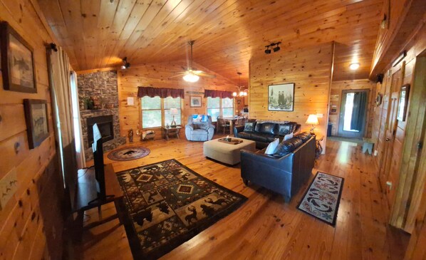 A wooden cabin interior with a fireplace, a sofa, a dining table, and a ceiling fan. - WHAT A VIEW from the HOT TUB! Ping-pong & Pac-Man game room! (Blue Ridge)