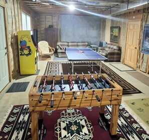 Une pièce équipée d’un baby-foot, de canapés et d’une table de ping-pong.