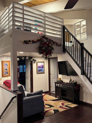 A multi-level living space with a staircase, a fireplace, and a television.