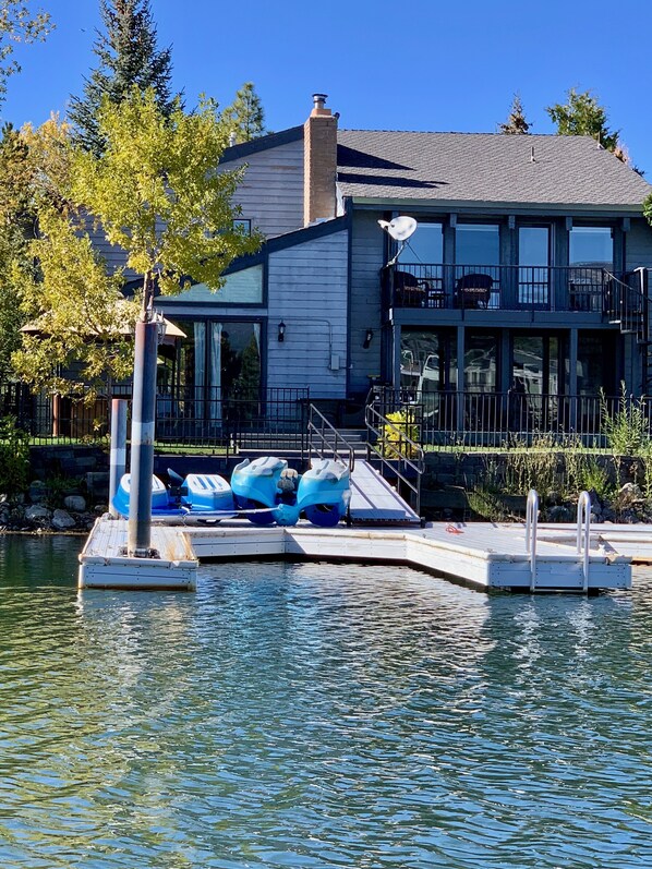 Un muelle con kayaks, un edificio de amplios ventanales y un cielo azul despejado.