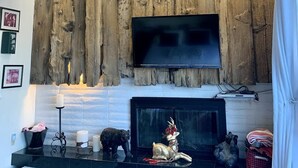 A living room with a large wooden wall, a fireplace, and a mounted TV. - Thanksgiving & Christmas-HEAVENLY-Waterfront-Mtn Views-HotTub-Pool Table-Dock (South Lake Tahoe)