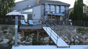 A waterfront property with a dock, a covered outdoor seating area, and a multi-level house with balconies. - Thanksgiving & Christmas-HEAVENLY-Waterfront-Mtn Views-HotTub-Pool Table-Dock (South Lake Tahoe)