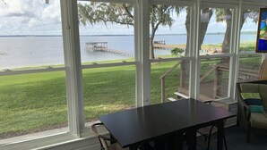 A room with large windows overlooking a lake, a dock, and a grassy area with a wooden deck. - Lake front on North shore of Lake Weir, Florida (it is NOT a duplex / 2 entries) (Ocklawaha)