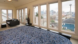 A bedroom with large windows, a bed, a sofa, and a view of a cityscape including a tower. - Luxury in Queen Anne very walkable! (Seattle)