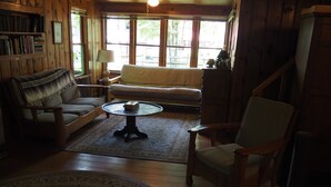 A cozy living room with a sofa, armchairs, a coffee table, and a rug. - Classic Vermont Cabin on 2.5 acres Lake Frontage (Salisbury)