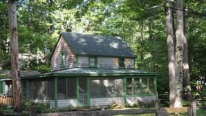 A wooden house with a green roof and a porch, surrounded by trees. - Classic Vermont Cabin on 2.5 acres Lake Frontage (Salisbury)