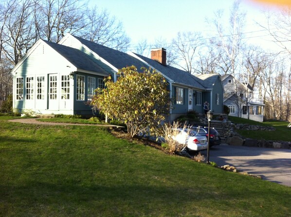 A two-story house with a sloped roof, a front porch, and a driveway with parked cars. - Beautiful vacation home in amazing location (York)