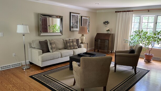 A living room with a sofa, two armchairs, a coffee table, a fireplace, and a large window with curtains. - Beautiful vacation home in amazing location (York)