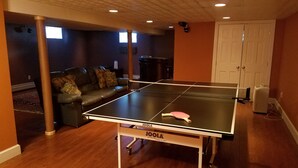 A ping pong table in a room with a dark brown wall, a leather sofa, and a white door. - Beautiful vacation home in amazing location (York)