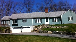 A two-story house with a stone retaining wall, a garage, and a well-maintained lawn. - Beautiful vacation home in amazing location (York)