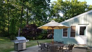 A patio with a grill, dining table, chairs, and an umbrella. - Beautiful vacation home in amazing location (York)