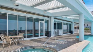 A pool area with a hot tub, lounge chairs, and a covered seating area.