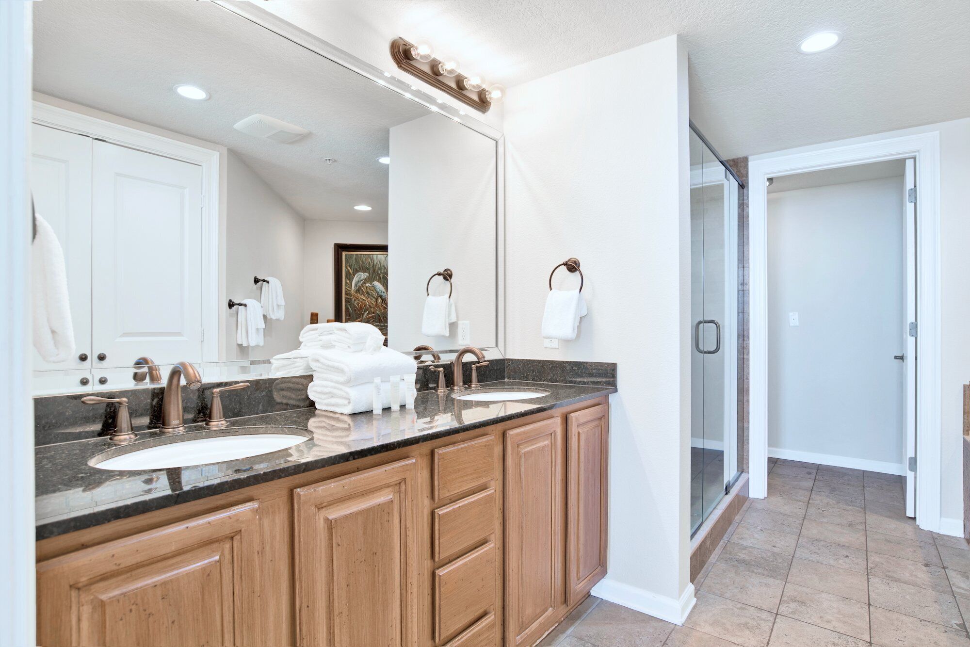 A modern bathroom with two sinks, wooden cabinets, and a large mirror.