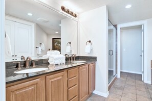 A modern bathroom with two sinks, wooden cabinets, and a large mirror.