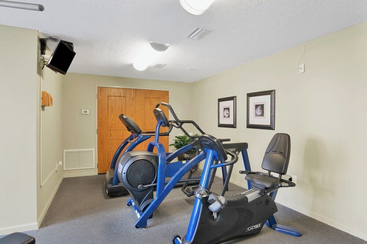 Een sportruimte met fitnessapparatuur, een deur en twee foto's in lijsten aan de muur.