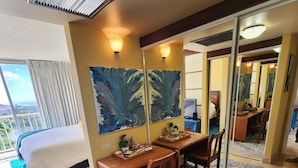 Habitación de hotel con cama, escritorio, silla, un espejo grande y vistas al exterior.