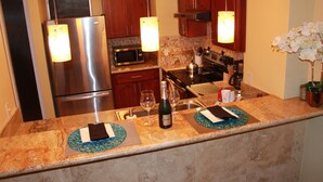 Una cocina moderna con electrodomésticos de acero inoxidable, encimeras de granito e iluminación colgante.