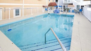 A rectangular pool with a metal ladder and a white fence.