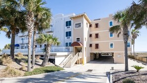 A beachfront hotel with multiple floors, a covered entrance, and palm trees.