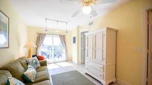 A room with a sofa, a white cabinet, a ceiling fan, and a view to the outside.