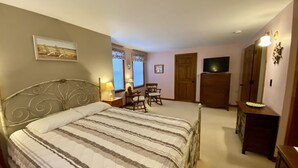 Un dormitorio con una cama grande, un escritorio, una silla, un aparador y un televisor.
