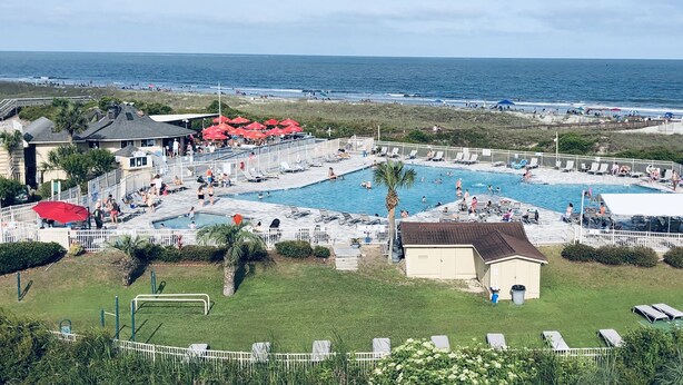 A resort with multiple swimming pools, a beach view, and a fenced area with lounge chairs. - Admiral’s Row B2 - 2nd floor corner condo.  Clean, comfy and relaxing (Hilton Head Island)