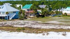 Il s’agit d’une propriété située sur la côte, comprenant plusieurs bâtiments, notamment une grande maison avec un toit bleu et une construction plus petite avec un toit vert.