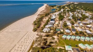 Vue aérienne d’une station balnéaire avec des propriétés situées en bord de mer, une plage de sable et une vue dégagée sur l’océan.
