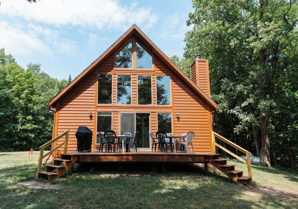 A wooden cabin with a deck, outdoor seating, and a chimney.