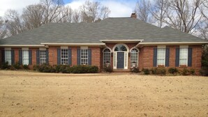 A two-story brick house with a front porch, a garage, and a large front lawn.