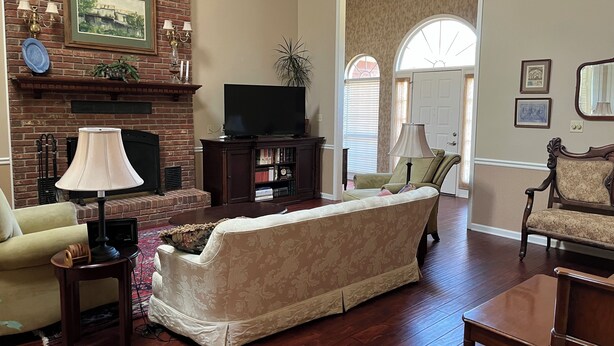 A living room with a brick fireplace, a television, a sofa, and a coffee table.