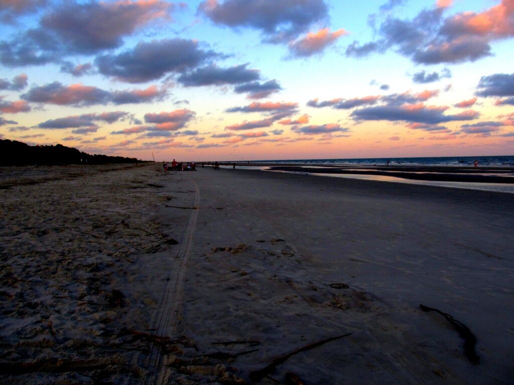 A beach with a clear sky and a few clouds.