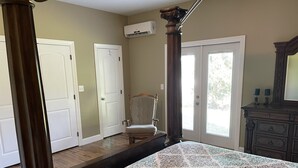 Une chambre à coucher avec un lit à baldaquin, une chaise, une commode et une porte avec une fenêtre.