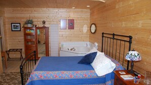A wooden cabin bedroom with a bed, a nightstand, a dresser, a wooden chair, a wooden cabinet, a bathtub, and a wooden ceiling.