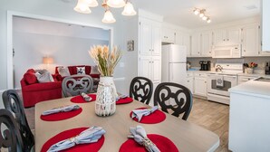 A modern kitchen with white cabinets, a microwave, and a stove. There is a dining table with red placemats and a vase of dried flowers. - Winter Discounts/We love pets! 6ft fenced in backyard and pet amenities. (Hanahan)