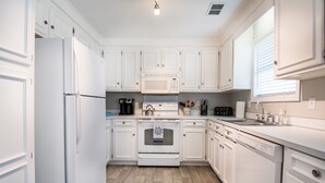 A modern kitchen with white cabinetry, a built-in oven, microwave, and dishwasher. - Winter Discounts/We love pets! 6ft fenced in backyard and pet amenities. (Hanahan)